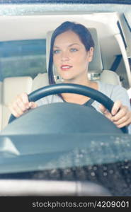 Attractive elegant businesswoman driving luxury new car smiling behind window