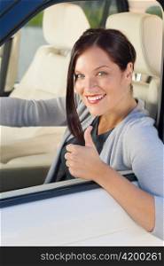 Attractive elegant businesswoman driving luxury new car thumb up smiling