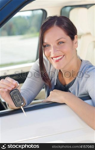 Attractive elegant businesswoman in new car showing keys smiling