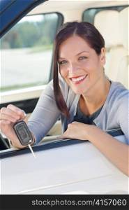 Attractive elegant businesswoman in new car showing keys smiling