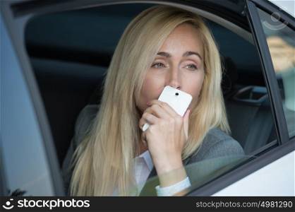 Attractive executive businesswoman sitting in car and calling by phone