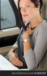 Attractive executive female manager sitting in car backseat calling hands-free