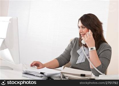Attractive executive woman on phone at office watching computer screen
