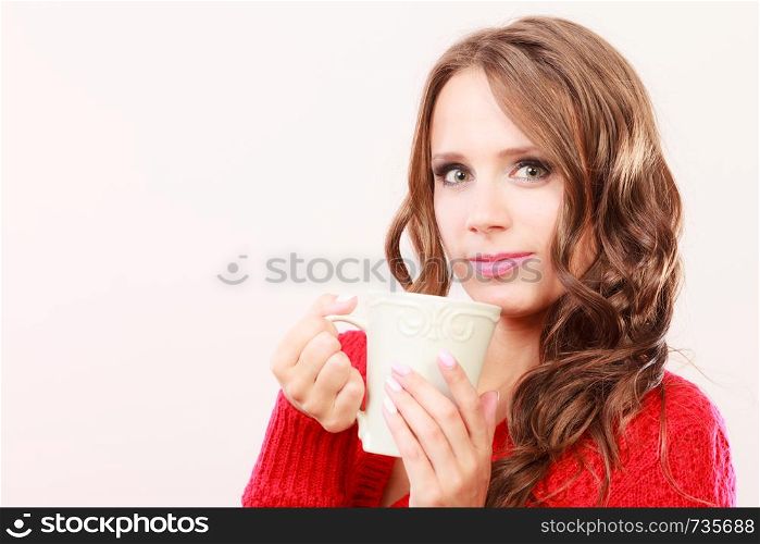Attractive fall girl long hair red autumnal sweater holding white mug with coffee warm beverage. Woman warming herself