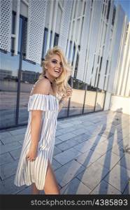 Attractive fashion blonde woman posing street style in white dress