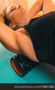 Attractive Female Athlete Stretching Back with Foam Roller. Foam Roller Back Stretching