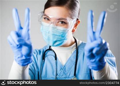 Attractive female caucasian doctor in uniform and protective personal equipment smiling and showing V sign symbol,Coronavirus COVID-19 virus disease pandemic outbreak crisis,patient hospital recovery 