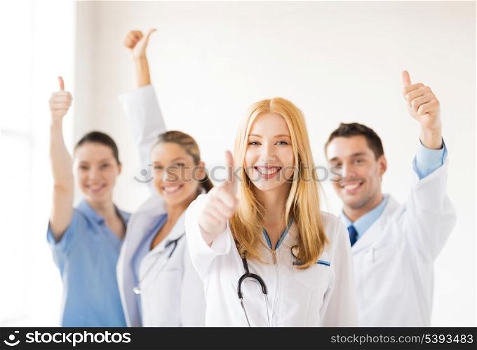 attractive female doctor with group of doctors showing thumbs up