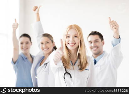 attractive female doctor with group of doctors showing thumbs up