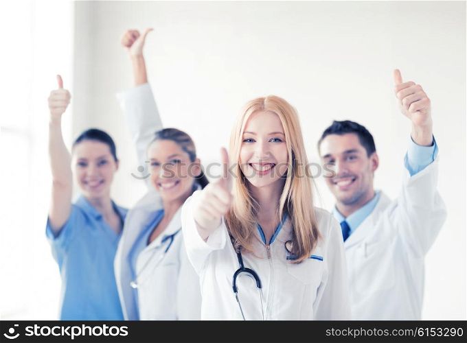 attractive female doctor with group of doctors showing thumbs up. group of doctors showing thumbs up