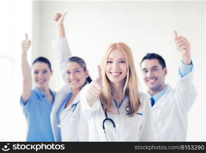 attractive female doctor with group of doctors showing thumbs up. group of doctors showing thumbs up