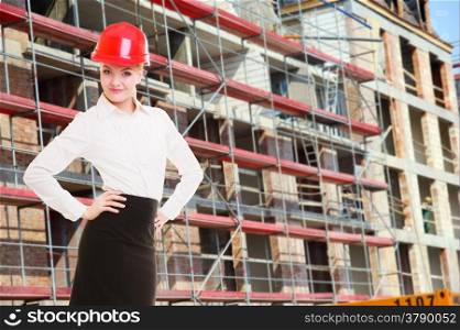 Attractive female engineer working. Woman architect in red safety helmet on construction site. Building.