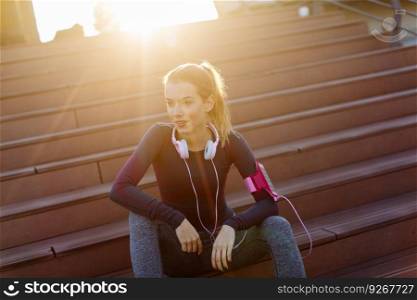 Attractive female  runner taking break after jogging outdoors