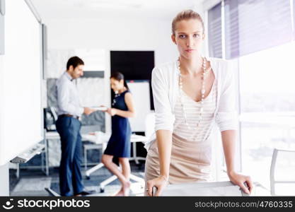 Attractive female worker in office. Attractive female woman in office with colleagues on background