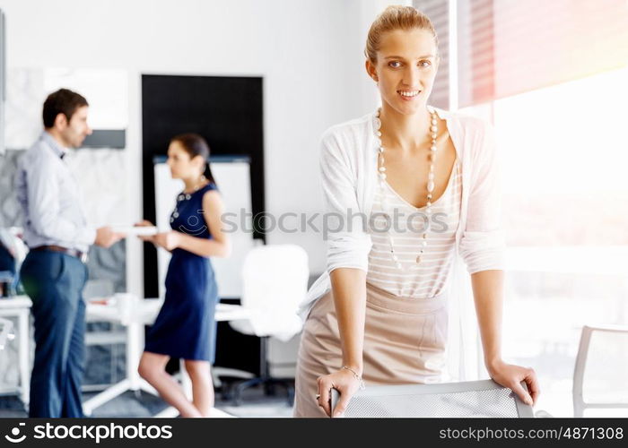 Attractive female worker in office. Attractive female woman in office with colleagues on background