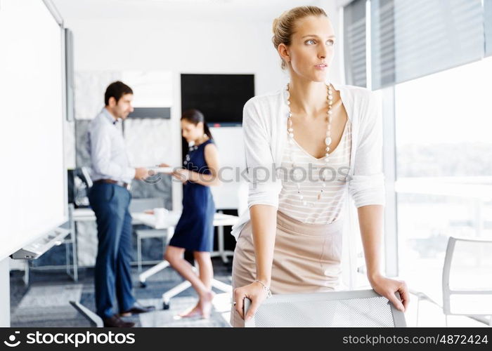 Attractive female worker in office. Attractive female woman in office with colleagues on background