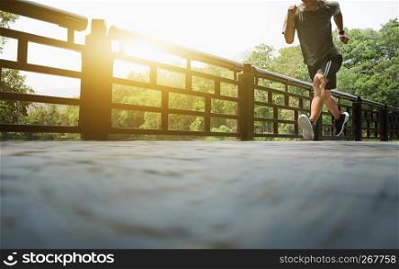 Attractive fit man running fast along bridge at a park, black man doing workout outdoors