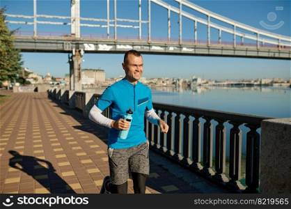 Attractive fit man running fast along the river. Jogger doing outdoors workout in morning. Attractive fit man running fast along the river