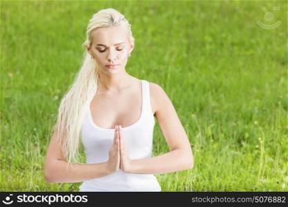 Attractive girl in lotus pose. Attractive girl in lotus pose over green grass background