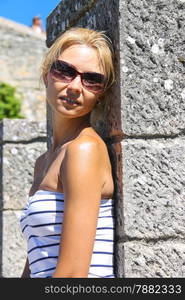 Attractive girl in sunglasses near the fortress wall