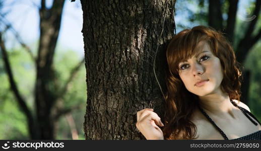 attractive girl leaning against a tree. outdoor shot