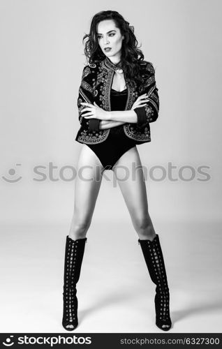 Attractive girl, model of fashion, wearing modern jacket, high boots and black lingerie. Female with long wavy hairstyle. Studio Shot.