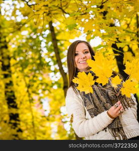 Attractive girl posing with maple leafs on autumnal park