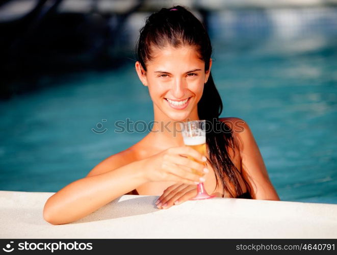 Attractive girl with a glass of champagne in the pool