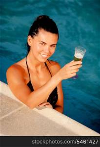 Attractive girl with a glass of champagne in the pool