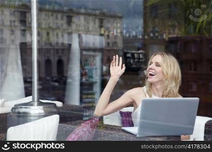 Attractive girl with a laptop waving to someone