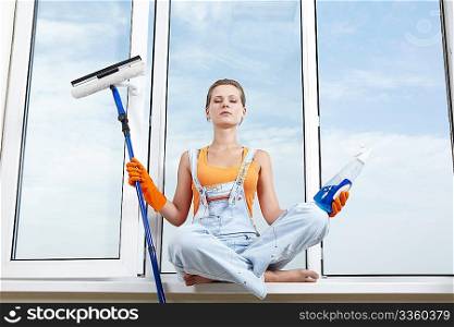 Attractive girl with detergents in the lotus position on the windowsill