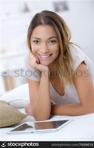 attractive girl with tablet laying on bed in modern apartment