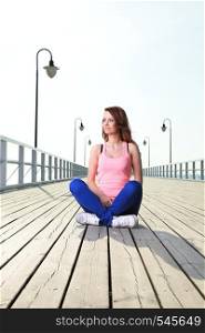 Attractive girl Young woman on pier Sits Crossed Legged Relaxing Old Wooden Pier