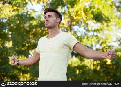 Attractive guy in the park with yellow t-shirt extending his strong arms