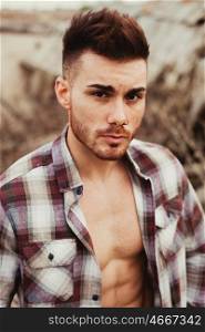 Attractive guy showing his strong chest and abs with the plaid shirt open