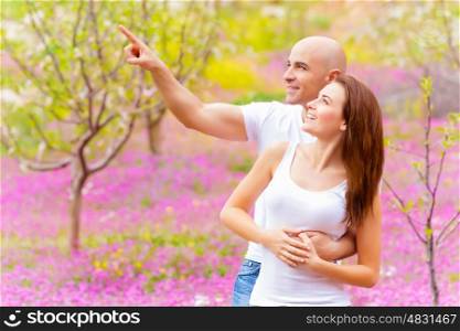 Attractive guy showing something in sky his lovely girlfriend, having fun in spring park, relaxation outdoors, romantic vacation concept&#xA;