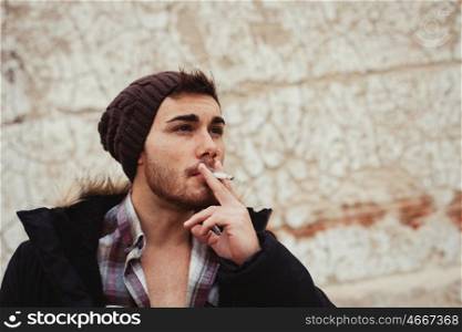 Attractive guy with black wool hat smoking at the street