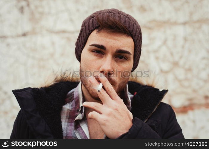 Attractive guy with black wool hat smoking at the street