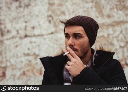 Attractive guy with black wool hat smoking at the street