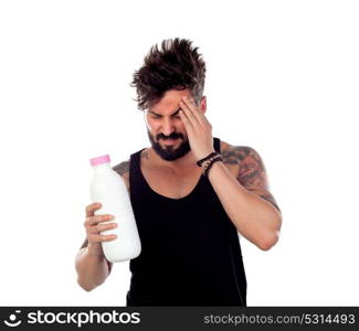 Attractive guy with headache holding a milk bottle isolated on a white background