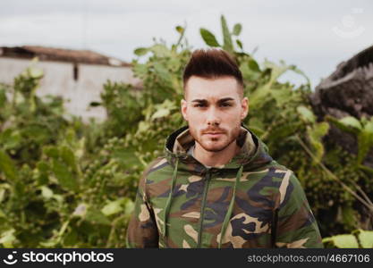 Attractive guy with military jacket and plants background