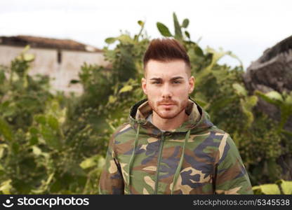 Attractive guy with military jacket and plants background