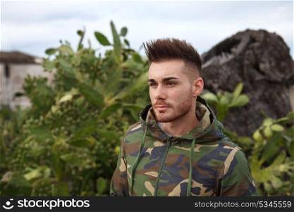 Attractive guy with military jacket and plants background