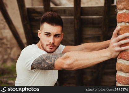 Attractive guy with white t-shirt next to a brick wall