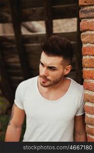 Attractive guy with white t-shirt next to a brick wall
