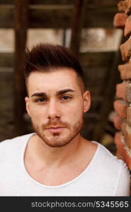 Attractive guy with white t-shirt next to a brick wall