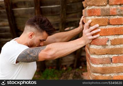 Attractive guy with white t-shirt next to a brick wall