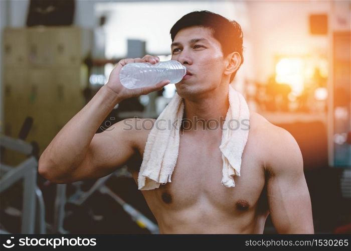 Attractive Handsome Asian young men holding drinking water after workout in gym cool down and relax muscle in strong body,Bodybuilder Concept