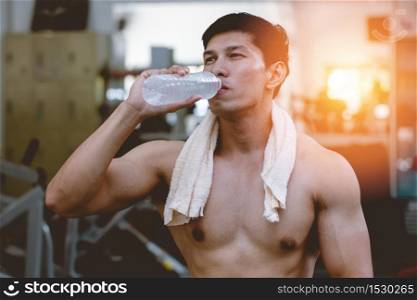 Attractive Handsome Asian young men holding drinking water after workout in gym cool down and relax muscle in strong body,Bodybuilder Concept