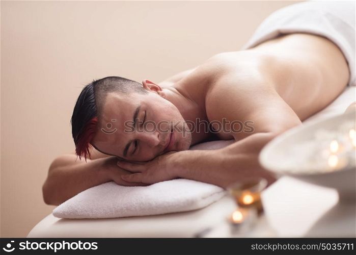 attractive handsome man resting in a spa massage center, lying on table relaxing closed eyes concept of men beauty health care